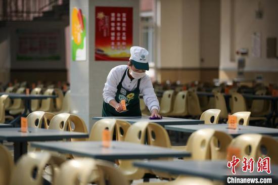 工作人员在学校食堂擦拭餐桌。 于海洋 摄