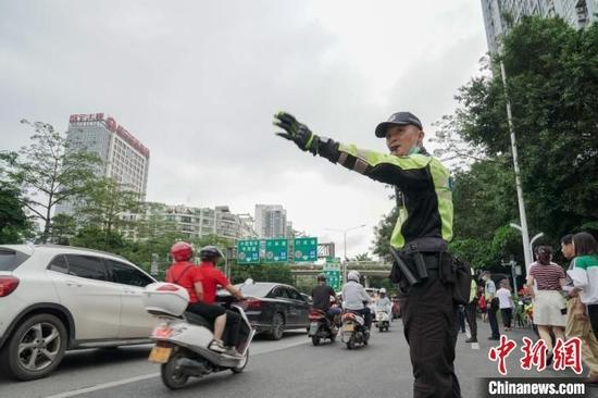 交警在考点外指挥交通,保证考生能准时参加考试。 王以照 摄
