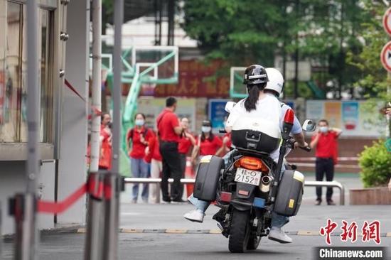 一位交警驾驶摩托车将办好临时身份证的考生送入考场。 王以照 摄