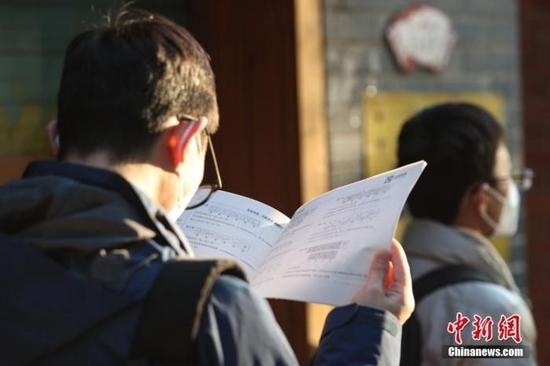 资料图:1月8日,江西南昌市第二十八中学考点外,一名考生拿着资料在复习。中新社记者 刘力鑫 摄
