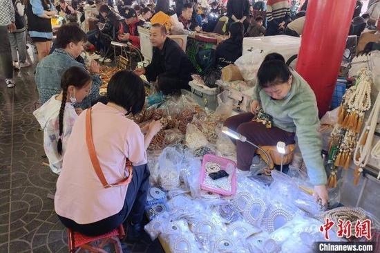 潘家园古玩市场,一位家长正在给孩子挑选菩提根手串。 左雨晴 摄