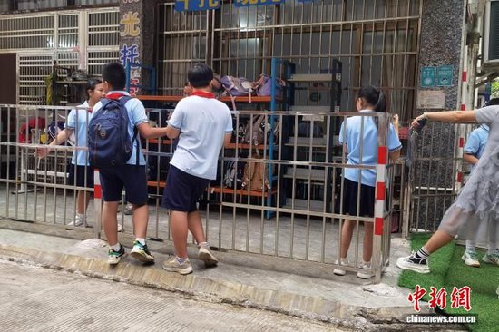 图为9月24日中午,广西北海几名小学生在等候家长接回。翟李强 摄