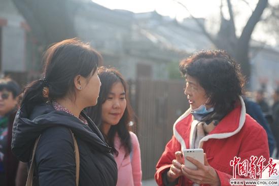 2月23日,中央戏剧学院,考生家长在学校门外等考生时,拿起手机分享备考经验。实习生 王艺霏/摄