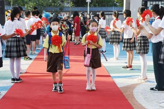 2021年9月1日,北京小学通州分校两名一年级新生戴着大红花走进校园。/视觉中国