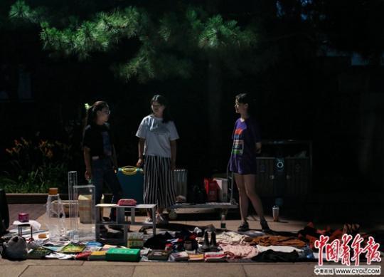 6月19日晚,中央美术学院毕业季跳蚤市场上,3名女学生站在自己的摊位前。临近毕业,不少大学生将自己闲置的服饰、书籍和生活用品运到校园广场上贩卖,许多校内师生和周边居民前来“淘宝”。中国青年报·中国青年网见习记者 孔斯琪/摄