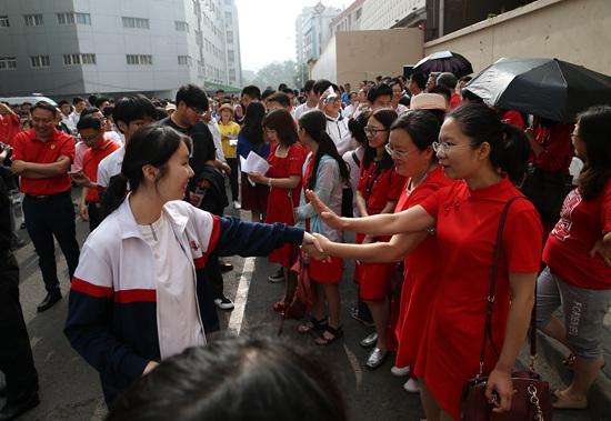 6月7日,北京陈经纶中学高考考点,身着红色衣服的老师与即将进入考场的考生们拉手鼓劲。当日,2019年全国高考正式拉开大幕,超千万考生奔赴考场。