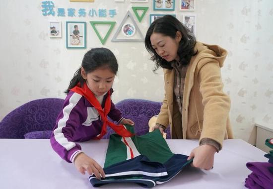 2021年11月10日,陕西平利县城关第三小学3年级1班的学生在学校内务整理室内学习叠衣服。 新华社记者 邵瑞 摄