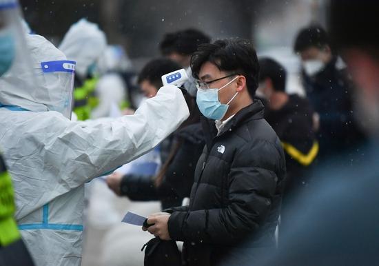 12月25日,在西安交通大学城市学院考点,工作人员为考生测温。新华社记者 张博文 摄