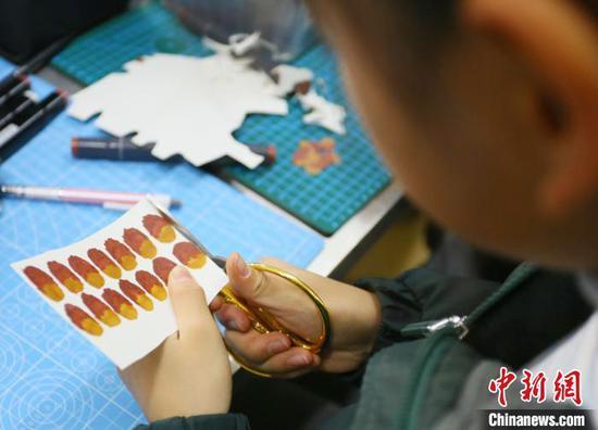 图为小学生将马克笔涂色的纸片进行裁剪。 高展 摄