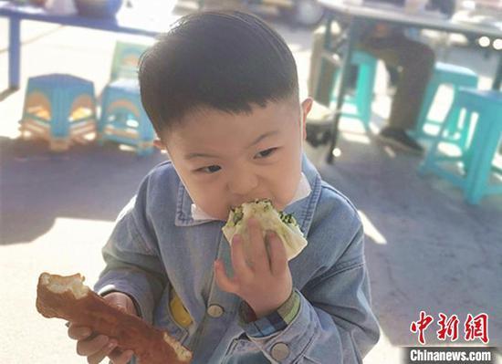 图为小朋友在幼儿园开设的早点摊吃早点。 张林虎 摄