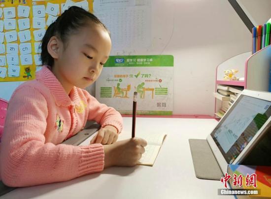 资料图:小学生们正在家中通过电脑、平板电脑等收看直播上课。中新社记者 翟羽佳 摄