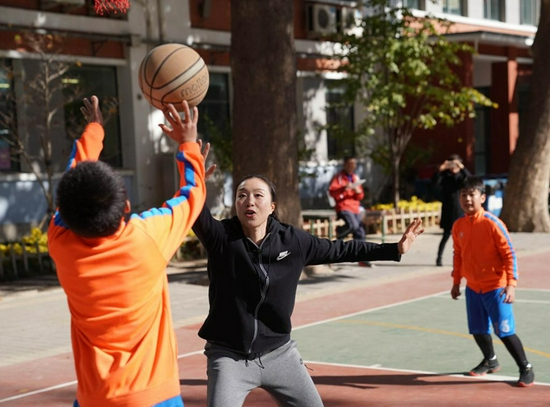 资料图:2018年10月31日,北京师范大学实验小学,中国女篮球员邵婷与小球员“切磋”球技。新华社记者孟永民摄