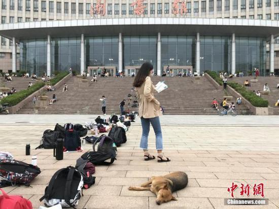 不少考生为抢占图书馆作为,用书包等站队。图为一名大学生在图书馆门前排队、背书。 韩章云 摄