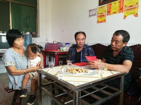 谭朝延(中)在贫困户家中走访(资料照片)。新华社发