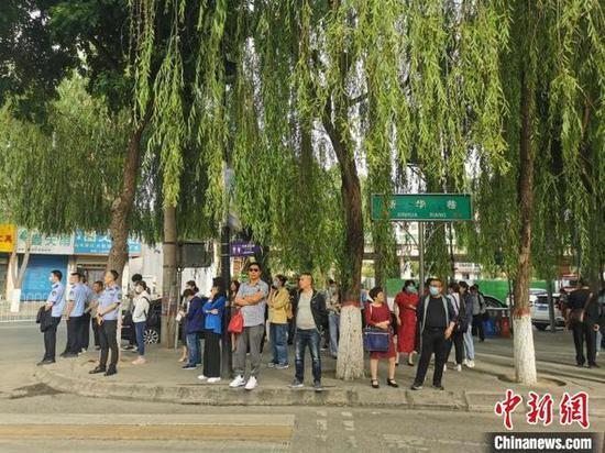 图为在考场外等候的家长,有不少家长身穿旗袍或大红色衣服为考生加油助威。 文思睿 摄