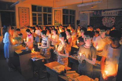 校园追思会现场,刚刚结束高考的高三学子点亮烛光,怀念前不久去世的数学老师卢雄英。