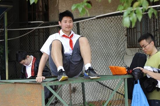 图为6月11日,在中国科大校园里拍摄毕业合影时,少年班学生王凯越爬上运动场的架子。