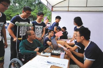 昨日,魏祥(坐轮椅者)在办理新生注册工作。 新华社发