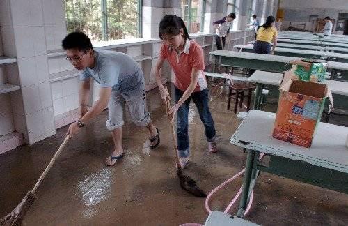 2006年,强降雨导致福建建瓯城区被淹,导致四千多名学生无法参加高考,图为学生打扫被淹的学校食堂。资料片