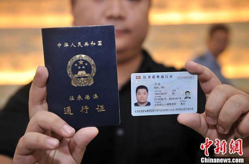资料图:市民展示电子往来港澳通行证(右一)和纸质港澳通行证(右二)。中新社发 陈超 摄