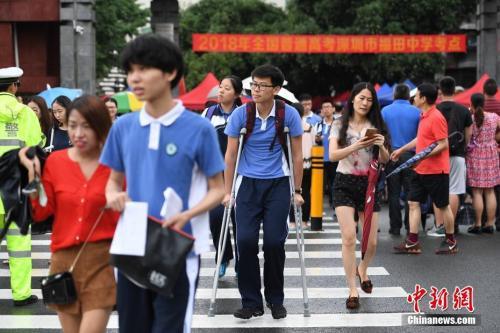 资料图:2018年6月7日,2018年高考进入第一天。图为福田中学考场外,一位高考生带伤上考场。中新社记者 陈文 摄