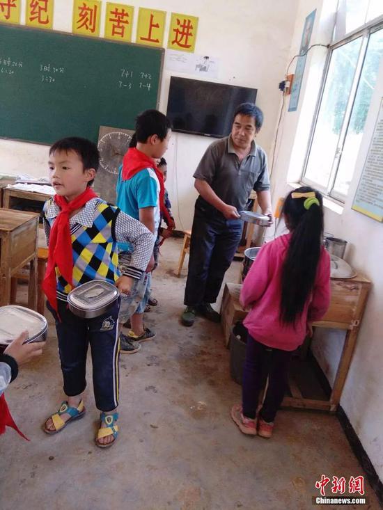 资料图,杨少成给学生热饭。受访者供图