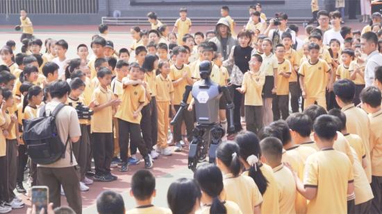 “天工”机器人走进北京第二实验小学,在操场上与同学们见面。