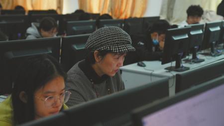 在课堂上认真听讲的周建(图中戴帽者)。
