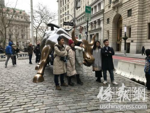 中国游客在华尔街铜牛旁拍照留念。(图片来源:美国侨报网记者华夏美佳摄)