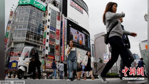 资料图片:2017年5月17日,日本东京新宿商业区,人们穿过街道。