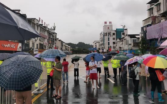7月7日,河道洪水漫上街道,警方在现场维持秩序。受访者供图
