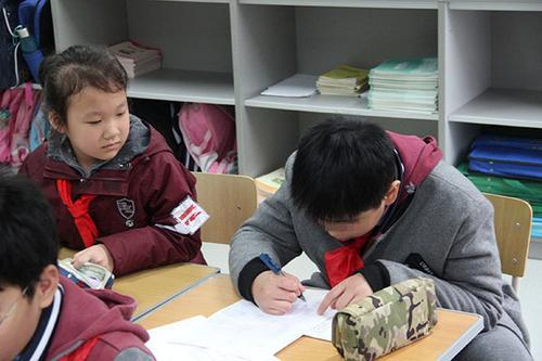 2017年11月29日,上海市闵行区平阳小学,自闭症男孩亨亨(右一)在写作业。本文图片均为 澎湃新闻记者 李菁 摄
