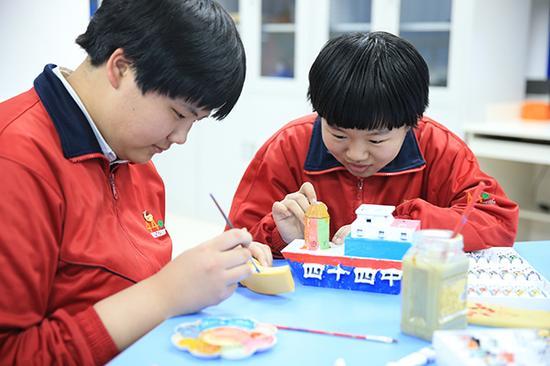 3D打印社团学生在社团活动室美化自己的3D打印作品。
