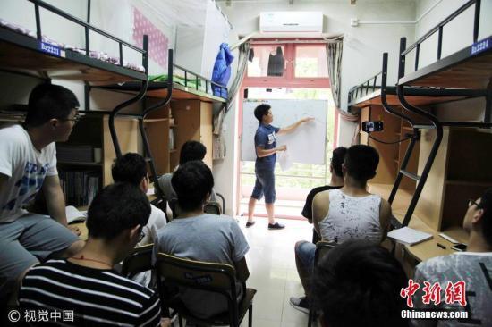 资料图:浙江农林大学大三学生李海明,在该校东湖校区B3222学生寝室里为班级的部分男生补课。图片来源:视觉中国