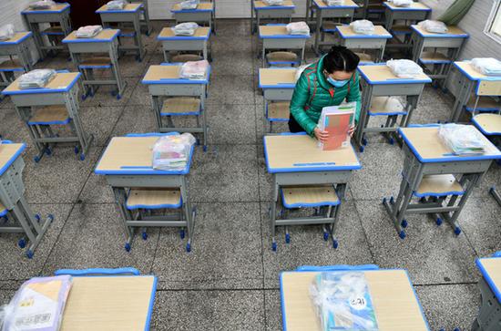 3月15日,在贵阳市云岩区第一小学初三年级集中教学点,老师为学生摆放和整理新课本。 新华社 图