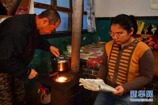 李彦昀(右)在静乐县新开岭村的家里一边烤火一边复习(3月23日摄)。 新华社记者 曹阳 摄