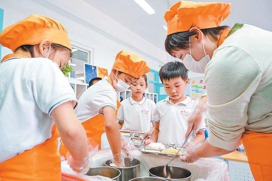 北京小学红山分校二年级教室内,班主任老师和两名“膳食小卫士”现场为同学们打饭。实习记者金瑶摄