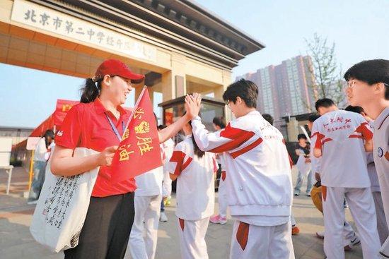 中考首日,北京市第二中学经开区学校考点门前,送考的老师为即将进入考场的学生们加油打气。本报记者 甘南摄