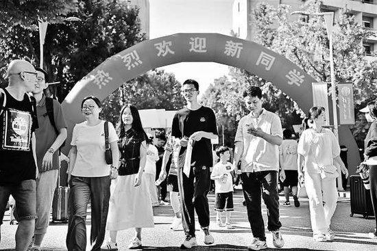 今天上午,清华大学新生及家长走过“热烈欢迎新同学”的红色拱门步入校园。 本报记者 和冠欣 摄