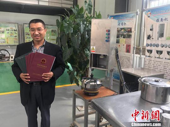 经过6年的概念开发和产品规划、详细设计、小规模生产等阶段,李万祥设计的第四代拉面机于2016年正式投产销售。图为李万祥和机器的合影。 艾庆龙 摄
