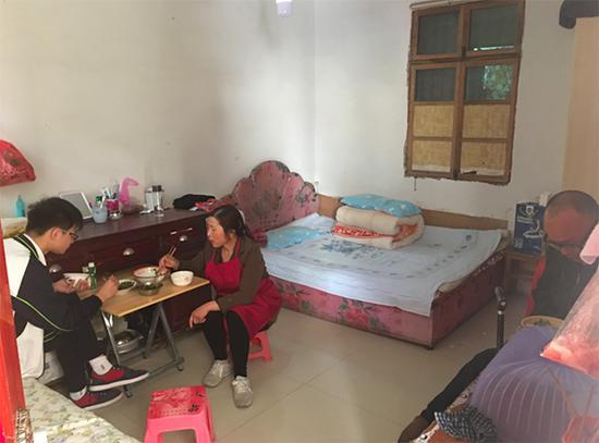 中午,胡仁荣一家在出租房里吃午饭。她的丈夫因行动不便,只能坐在靠墙的书桌边。