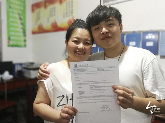 张杰举着香港中文大学的录取通知书和母亲合影留念。 图片来源:今贵州新闻客户端