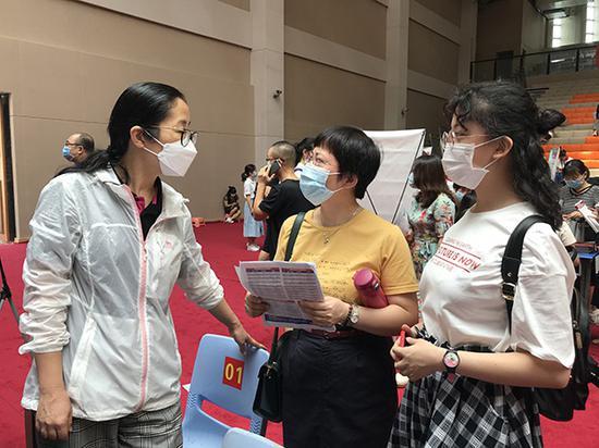 家长和考生阅览着各大高校招生简章,认真地和招生老师咨询讨教院校和专业。