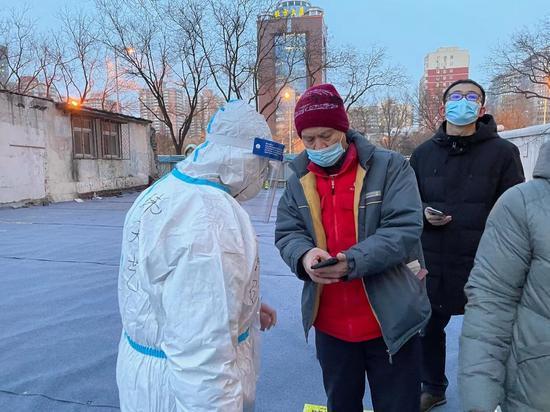志愿者协助居民扫码登记。首经贸供图