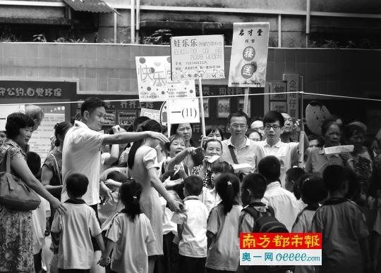 学生托管需求大,如何规范这一市场仍是问题。9月5日中午,铁一小附近,举着牌子的托管机构人员和家长一起接孩子放学。南都记者 冯宙锋 摄