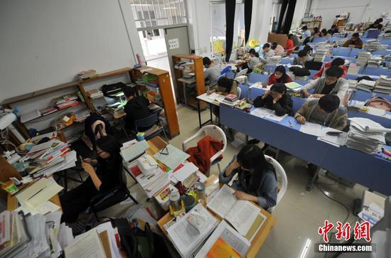 12月22日,福州一所大学校园内,考研专用教室里的桌面上堆满了学生们的各种复习资料。 张斌 摄
