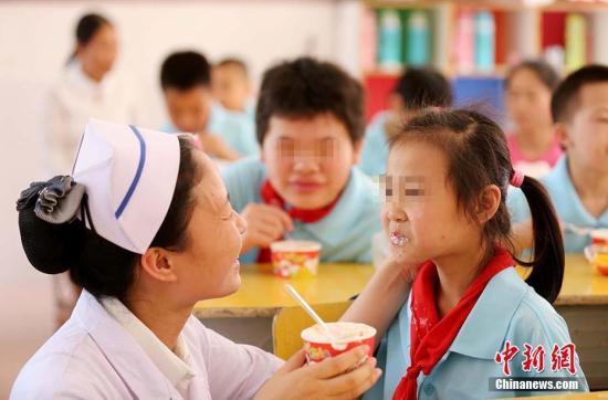 特殊教育学校,一名医护人员在喂学生吃蛋糕(资料图)。 谭凯兴 摄