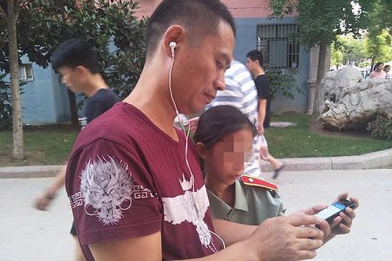 父亲正让女儿参与一场视频直播采访。摄影:刘成伟