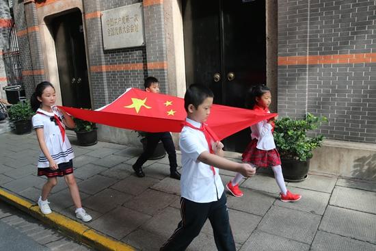 齐步,走!4名少先队员护旗手在上海市黄浦区中共一大会址护送五星红旗。《青年报》吴恺/摄