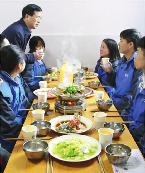 1月17日,湖南师大二附中食堂餐厅,校长张胜利端着饮料和学生们在餐桌上交流。潇湘晨报 图